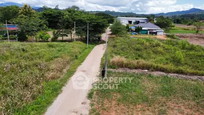 Scenic rural landscape with dirt road and distant buildings, ideal for development opportunities.