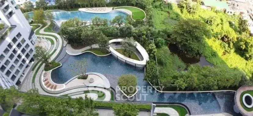 Luxurious aerial view of modern residential complex with stunning landscaped pool and lush greenery.