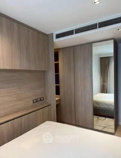 Modern bedroom with wooden built-in wardrobe and sleek design.