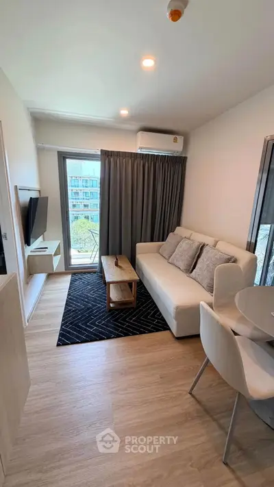 Modern living room with cozy sofa, wall-mounted TV, and balcony view in stylish apartment.