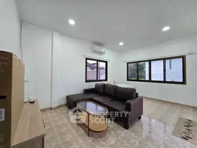 Spacious living room with modern sofa and large windows offering natural light.