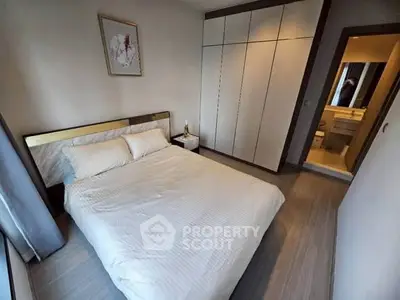 Modern bedroom with elegant decor and ensuite bathroom in a stylish apartment.