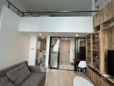 Modern loft apartment with mezzanine, stylish living area, and sleek glass partition.