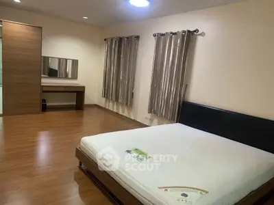 Spacious bedroom with wooden flooring and modern furnishings in a stylish apartment.