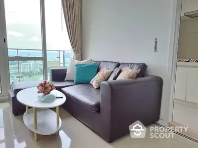 Bright and airy living room with a plush sofa set and a modern coffee table, leading to a balcony with a view.