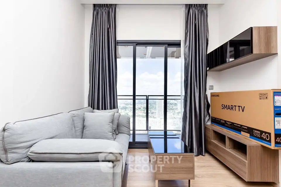 Modern living room with balcony view, featuring sleek furniture and a new smart TV in a stylish apartment.