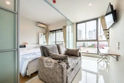 Modern studio apartment with large windows and city view, featuring a cozy living area and bedroom.