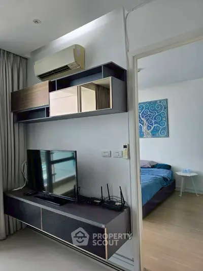 Modern living room with wall-mounted TV and air conditioning, adjacent to a cozy bedroom.