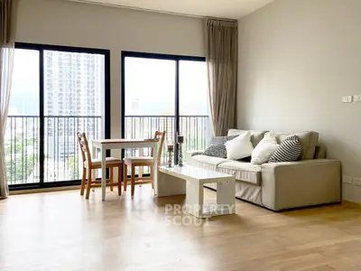 Spacious living room with large windows and modern furniture in a high-rise apartment.