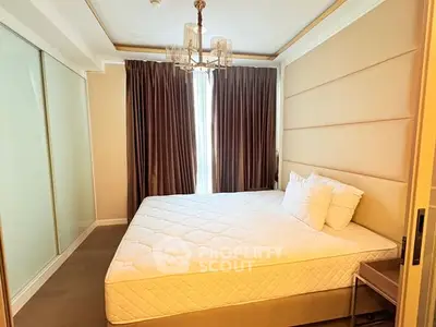 Luxurious bedroom with elegant chandelier and large bed in modern apartment.