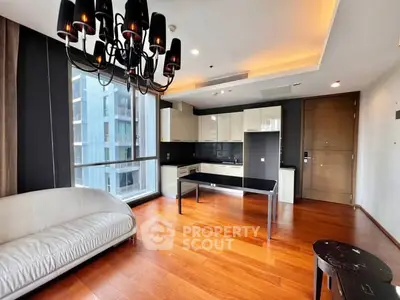 Modern living room with elegant chandelier and open kitchen layout in luxury apartment.