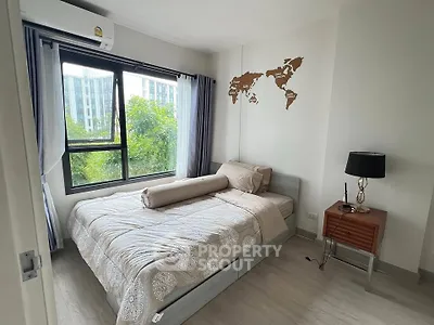Cozy bedroom with modern decor and large window offering a lush green view, perfect for relaxation.