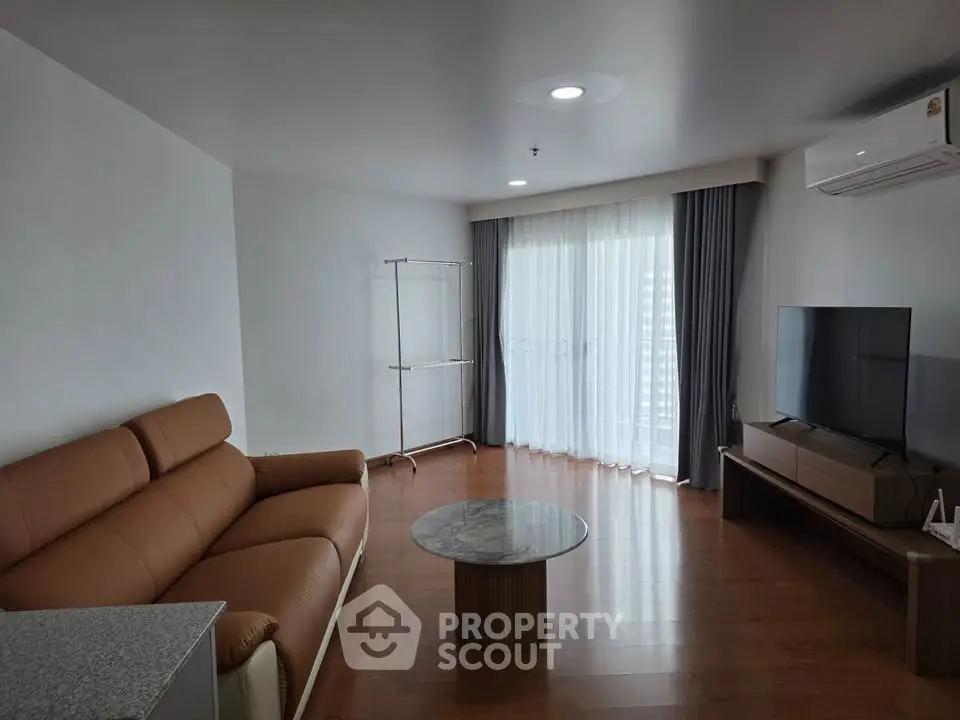 Spacious modern living room with leather sofa and large TV, perfect for relaxation.