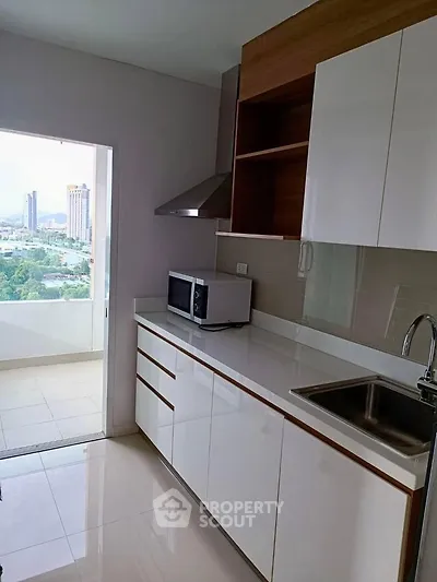 Modern kitchen with sleek cabinetry and city view from balcony