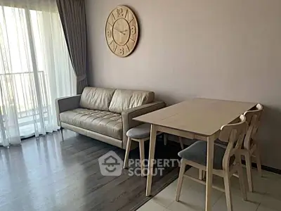 Modern living room with stylish furniture and large clock, featuring natural light and balcony access.