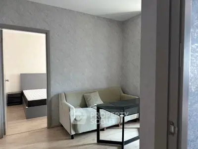 Cozy living room with modern sofa and glass table, adjacent to a bedroom with a stylish bed.