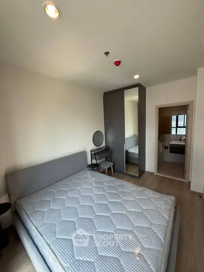 Modern bedroom with stylish furniture and ensuite bathroom in a contemporary apartment.
