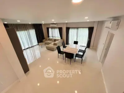 Spacious modern living room with elegant dining area and large windows.