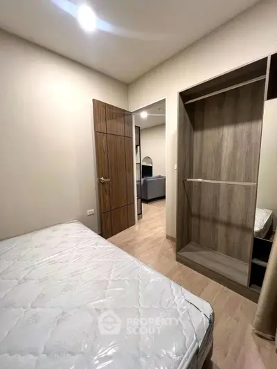Cozy bedroom with wooden flooring and built-in wardrobe, perfect for modern living.