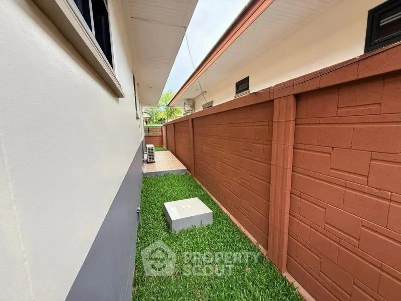 Side yard with grass and brick wall in modern residential property