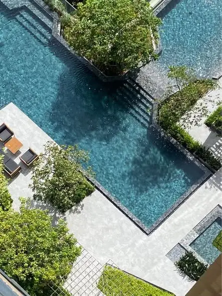 Luxurious aerial view of a modern swimming pool surrounded by lush greenery and stylish seating area.