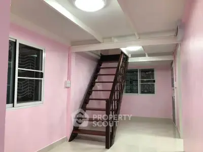 Charming pink-walled interior with wooden staircase, perfect for cozy living spaces.