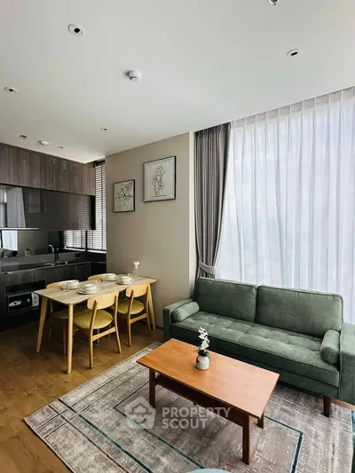 Modern living room with open kitchen, stylish furniture, and large windows for natural light.