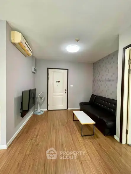 Modern living room with sleek black sofa, wall-mounted TV, and stylish wooden flooring.