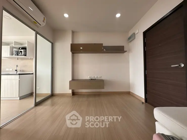 Modern living room with wooden flooring and open kitchen layout in a stylish apartment.