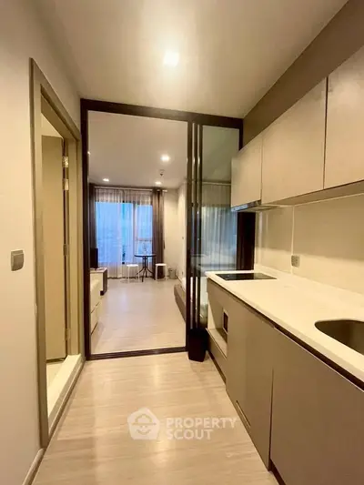 Modern kitchen with sleek cabinetry and open layout leading to a bright living area.
