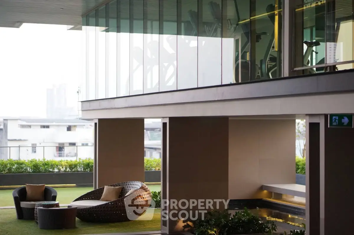 Luxurious modern building with outdoor seating and gym view, perfect for urban living.