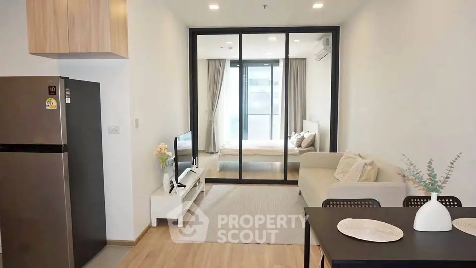 Modern open-plan living room with sleek kitchen and cozy bedroom view.