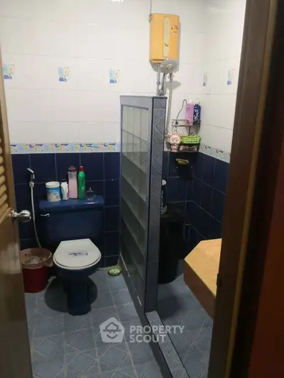 Cozy bathroom with blue tiles and modern shower partition, featuring essential amenities for comfort.
