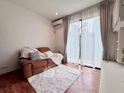Cozy living room with modern decor and natural light, featuring a comfortable sofa and elegant curtains.