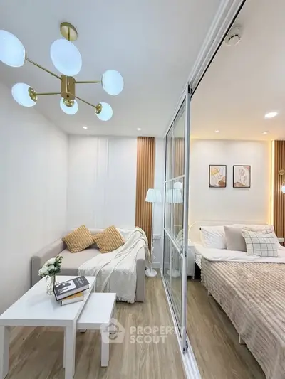 Modern living room with cozy sofa and elegant bedroom separated by glass partition.