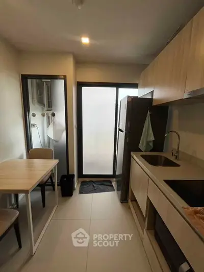 Modern kitchen with sleek cabinetry and dining area in a cozy apartment setting.