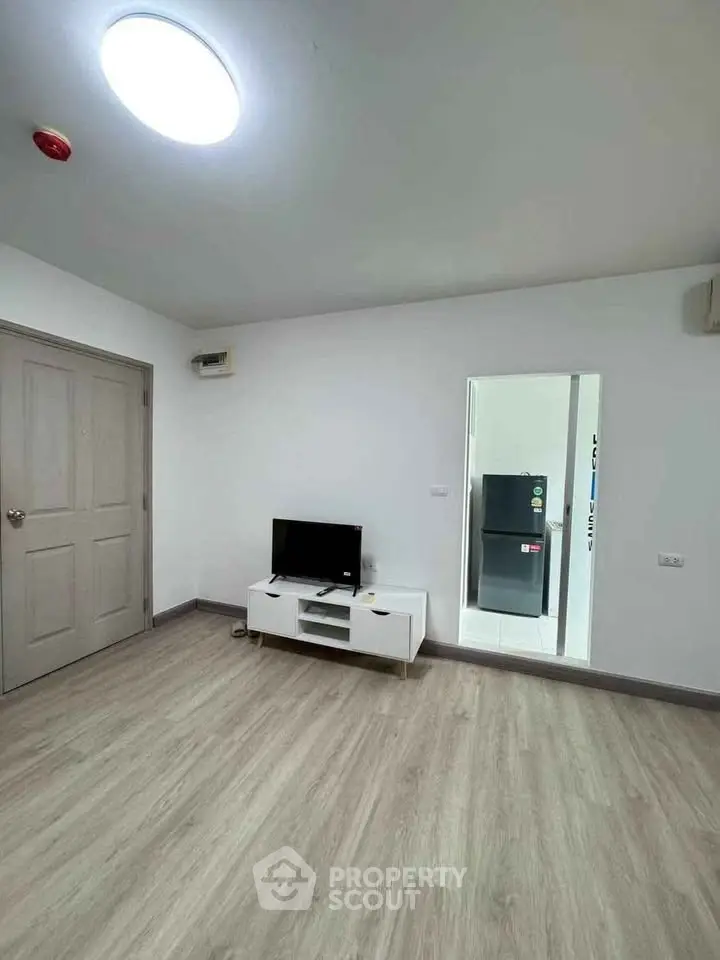 Spacious living room with modern flooring and TV setup, ideal for cozy living.
