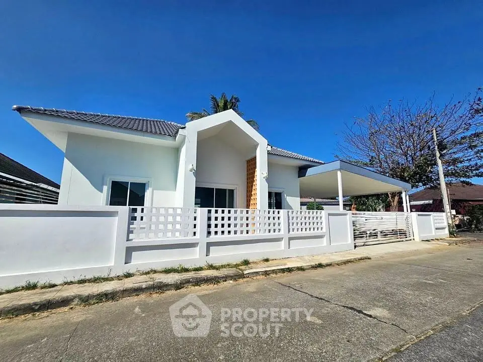 Charming single-story white house with modern design and spacious front yard in a serene neighborhood.