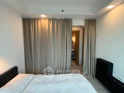 Modern bedroom with elegant curtains and cozy lighting, featuring a glimpse of a stylish bathroom.