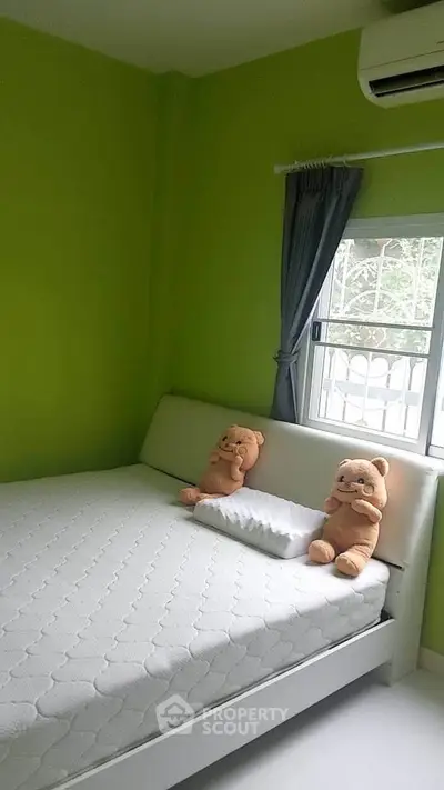 Cozy bedroom with green walls, plush toys, and window view