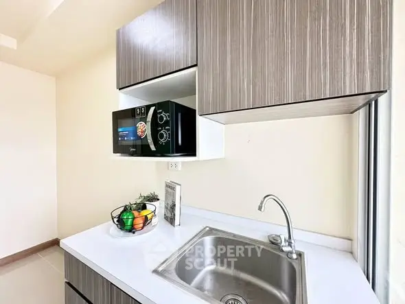 Modern kitchen with sleek cabinetry and built-in microwave, featuring a stylish sink and countertop.