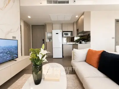 Modern living room with open kitchen, stylish decor, and city view from window.