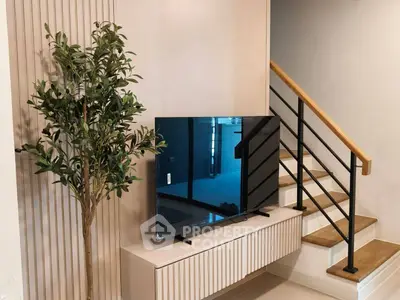 Modern living room with stylish TV setup and elegant staircase