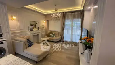 Elegant living room with chandelier and cozy seating area, featuring modern decor and ambient lighting.