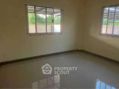 Spacious empty room with tiled flooring and large windows for natural light.