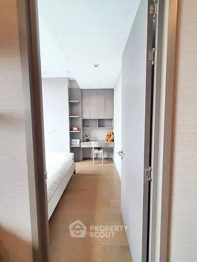 Modern bedroom with sleek design and built-in storage, featuring a cozy bed and wooden flooring.