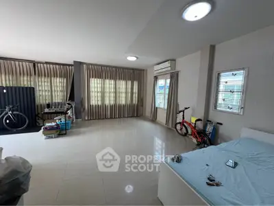 Spacious room with large windows, modern lighting, and tiled flooring, ideal for versatile living arrangements.