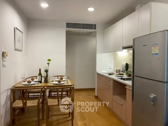 Charming kitchen with dining area, featuring modern appliances and cozy wooden furniture, perfect for intimate meals.