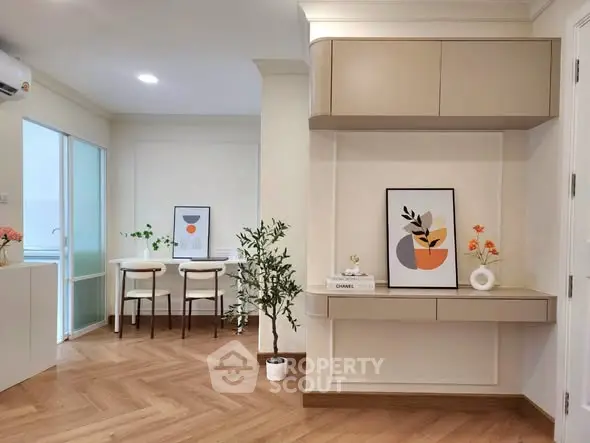 Modern living room with stylish decor and wooden flooring, featuring a cozy dining area and elegant wall art.