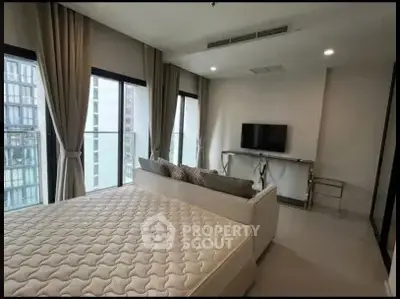 Modern bedroom with large windows and city view, featuring a stylish bed and wall-mounted TV.